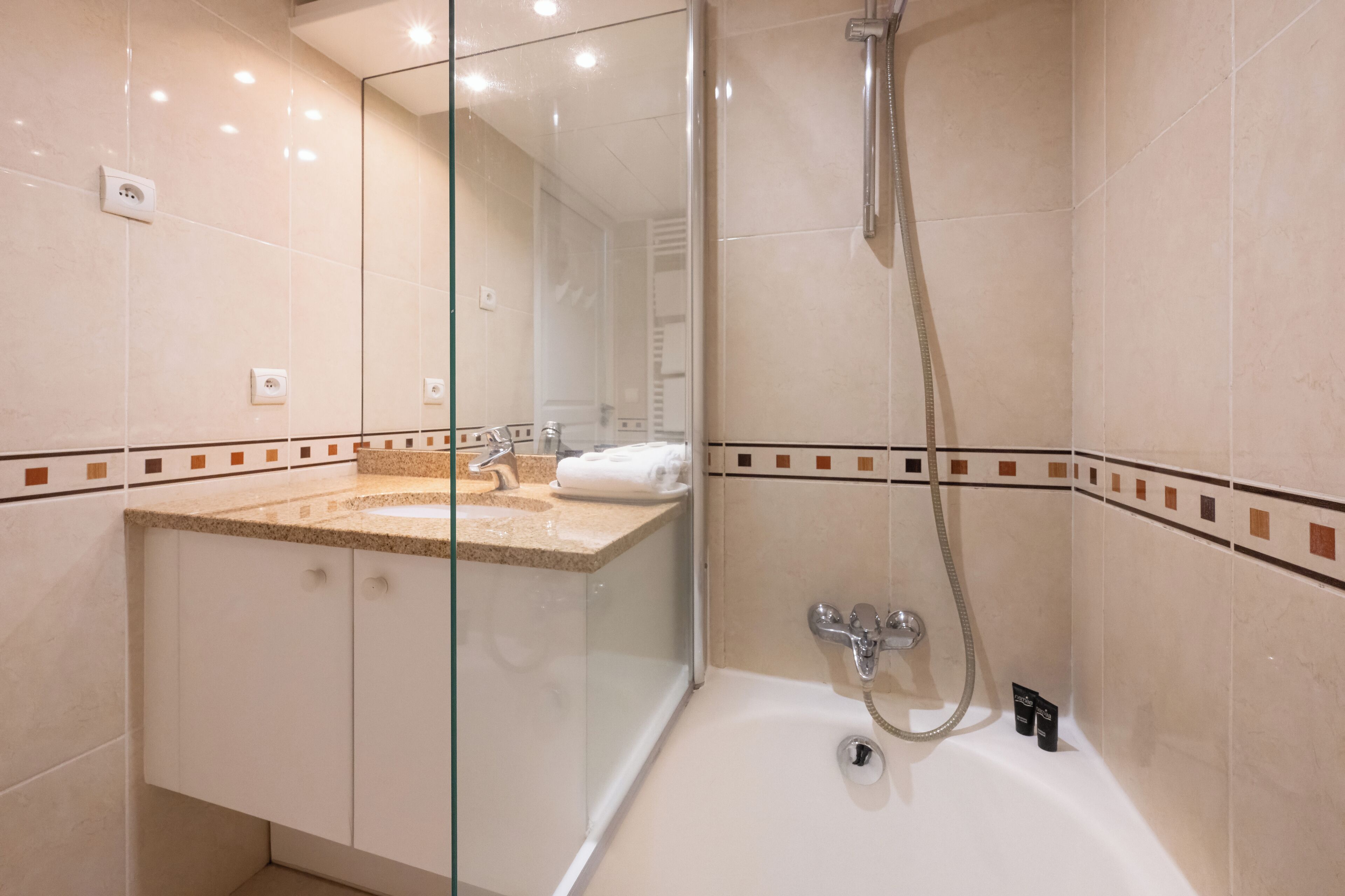Une salle de bain moderne dotée d’une douche à parois de verre, d’une baignoire et d’un meuble-lavabo avec un évier et un porte-serviettes.