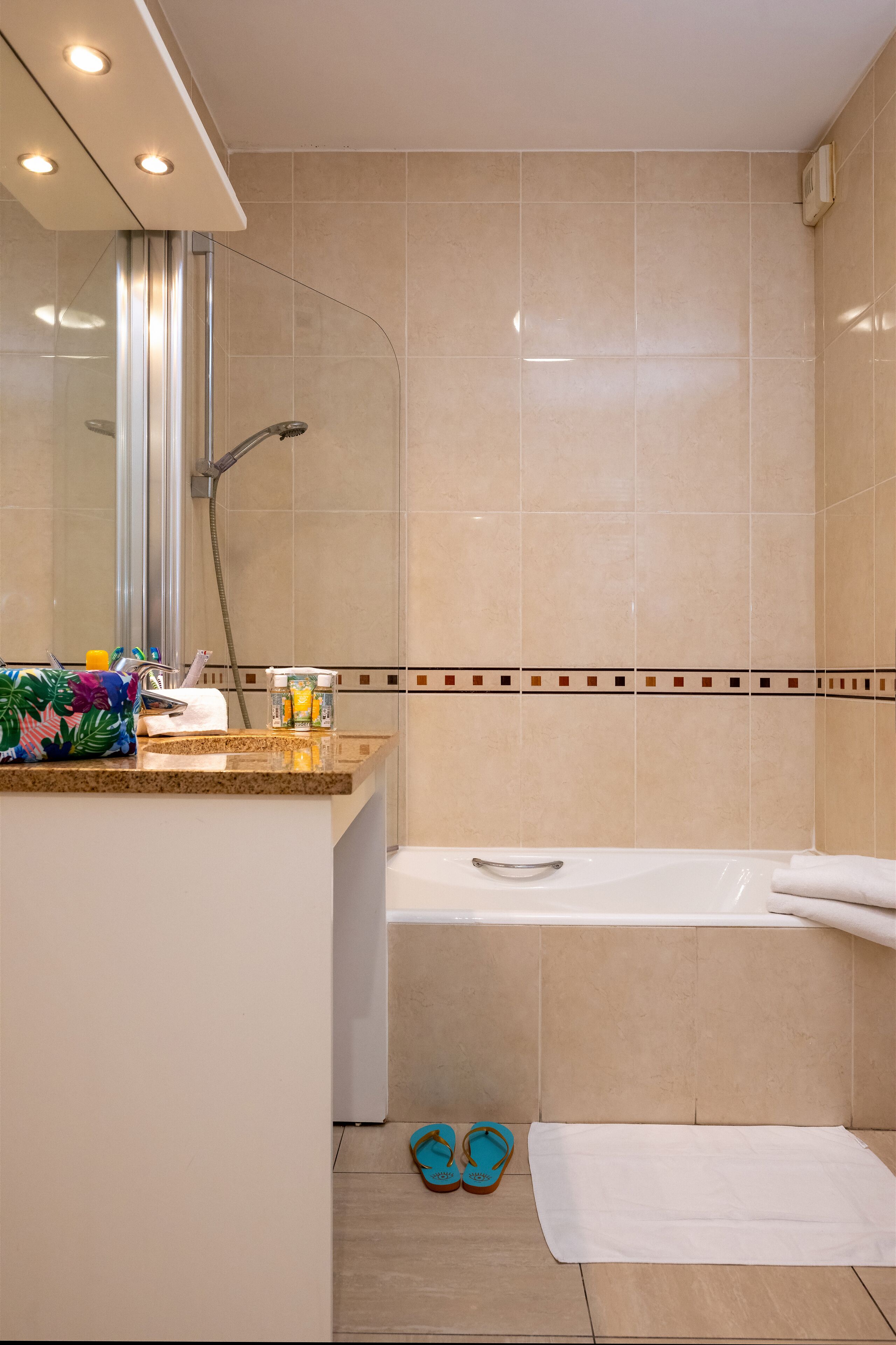 Un bagno con vasca, doccia e mobile lavabo con articoli da toilette.