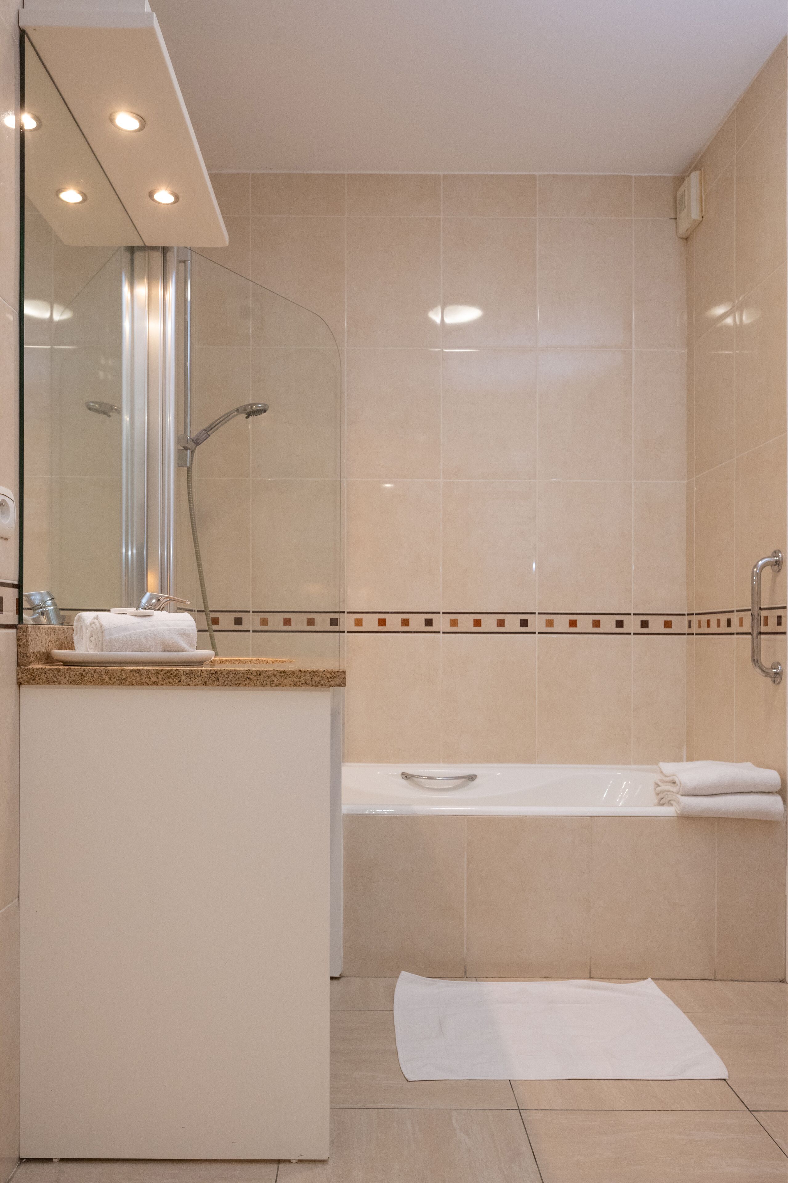 A modern bathroom with a glass-enclosed shower, a bathtub, and a vanity with a mirror.