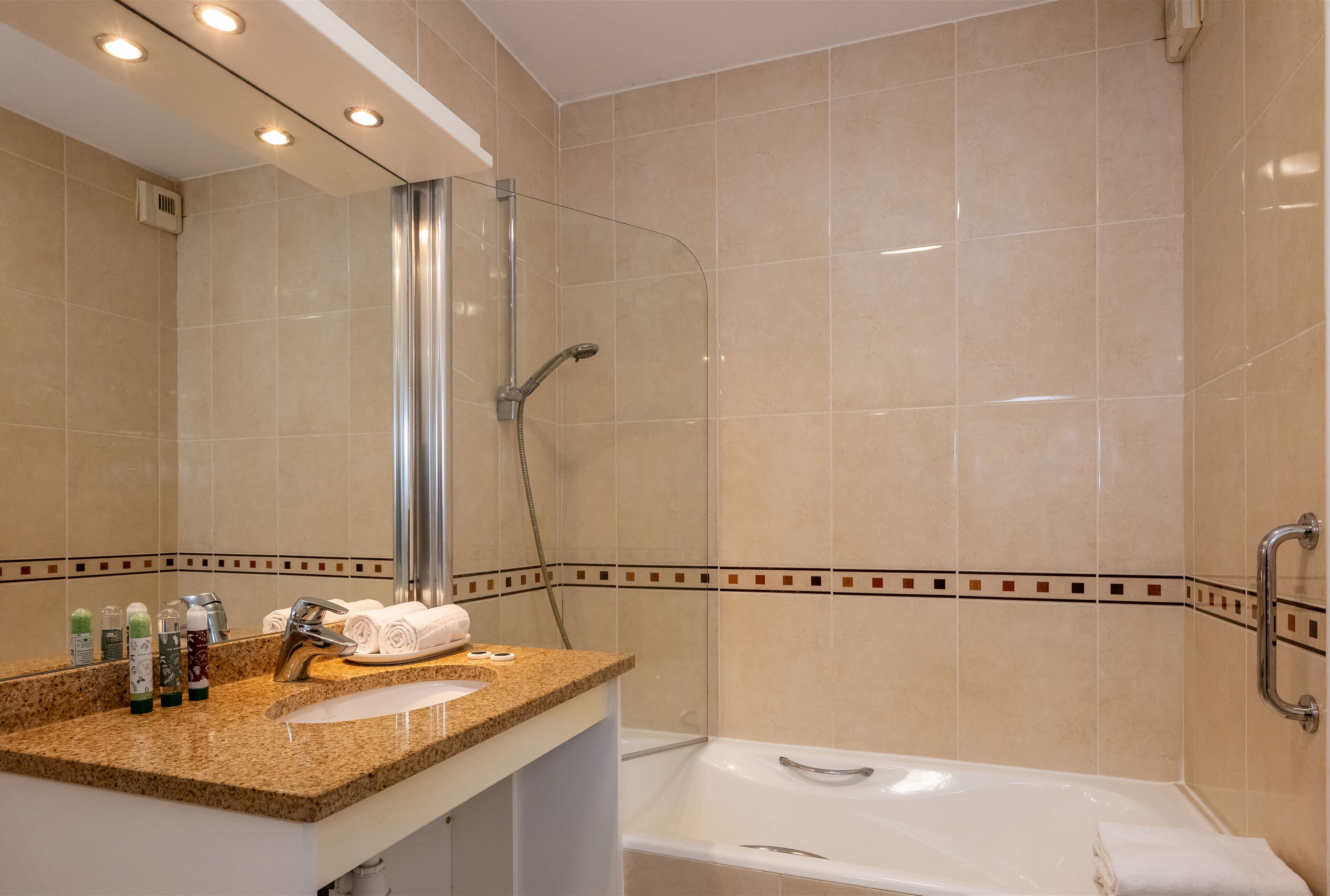 A bathroom with a shower, a sink with toiletries, and a bathtub.