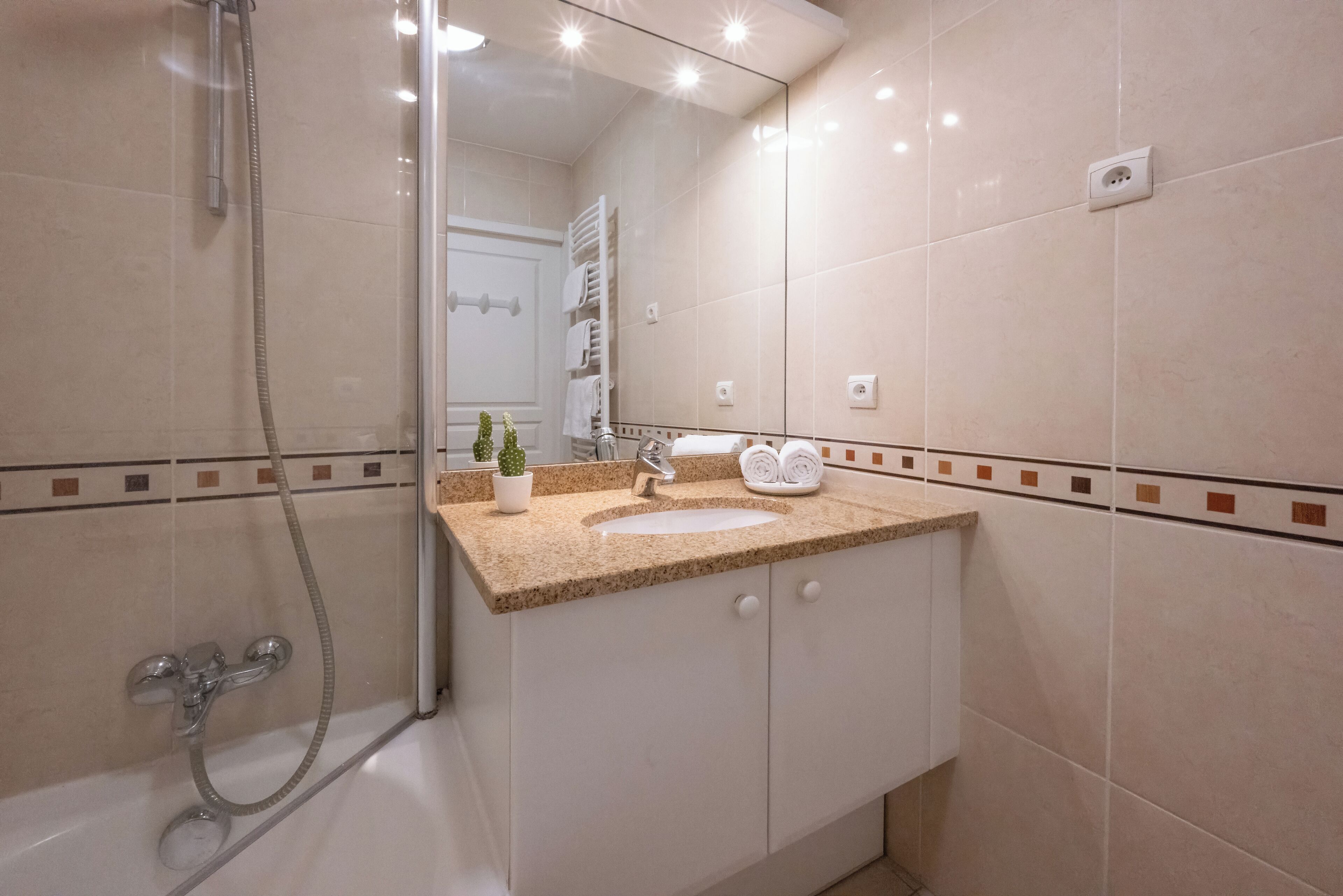 Une salle de bain moderne équipée d’une douche, d’un lavabo et d’un grand miroir.