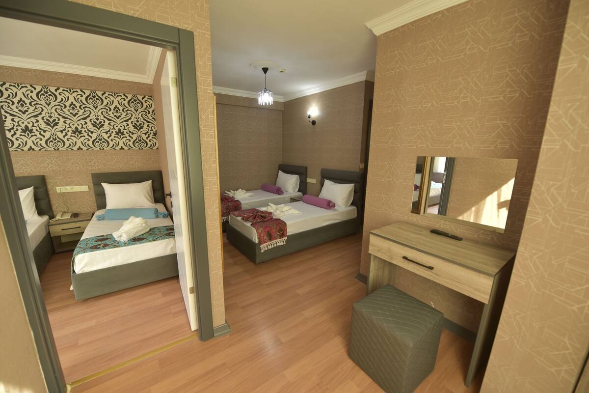 A hotel room with two beds, a desk, a chair, and a mirror.
