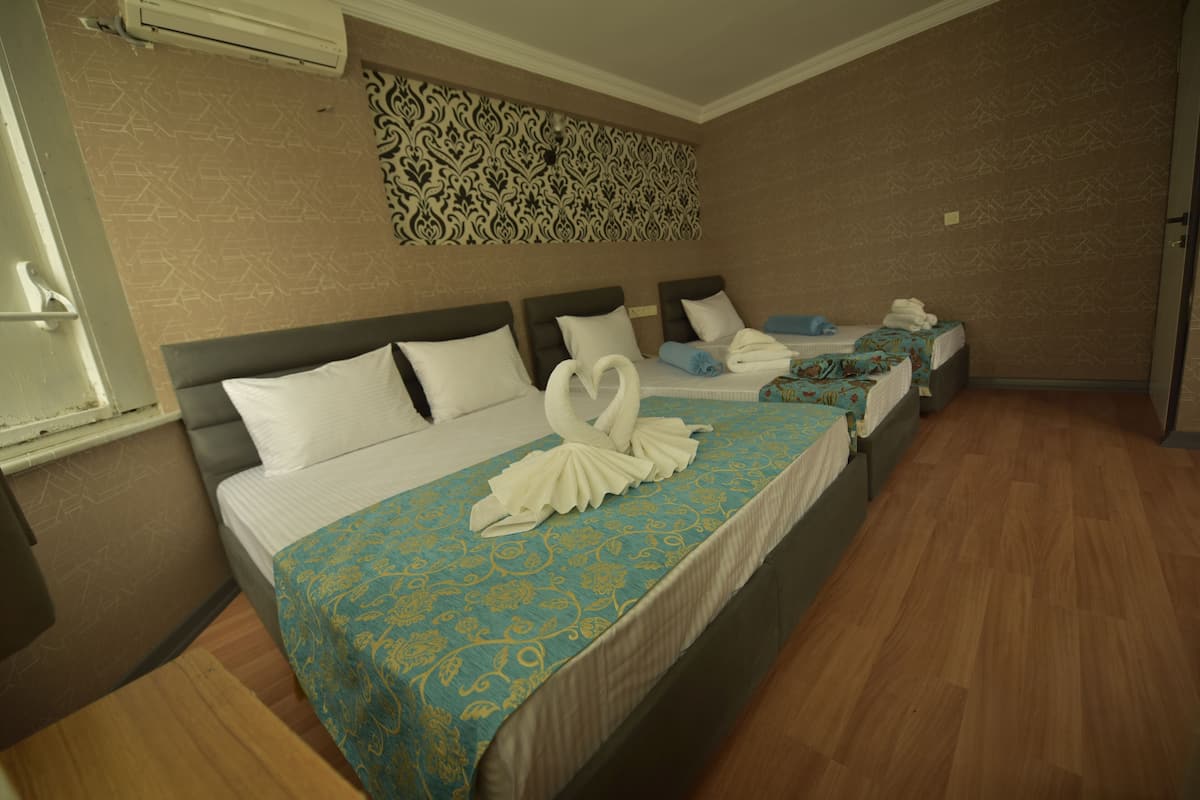 A hotel room with three beds, each with a blue and white patterned bedspread, and a decorative wall hanging above the beds.