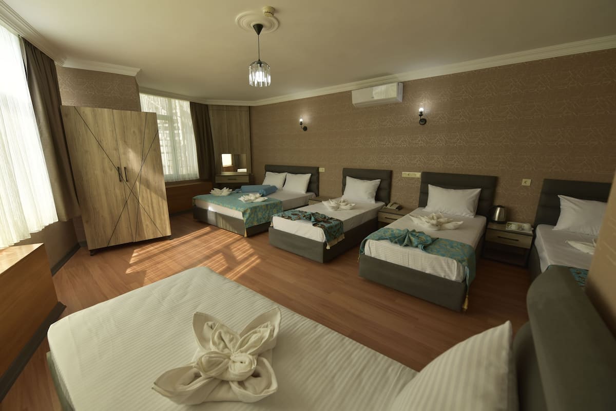 A hotel room with two single beds, a double bed, a wardrobe, and a desk.