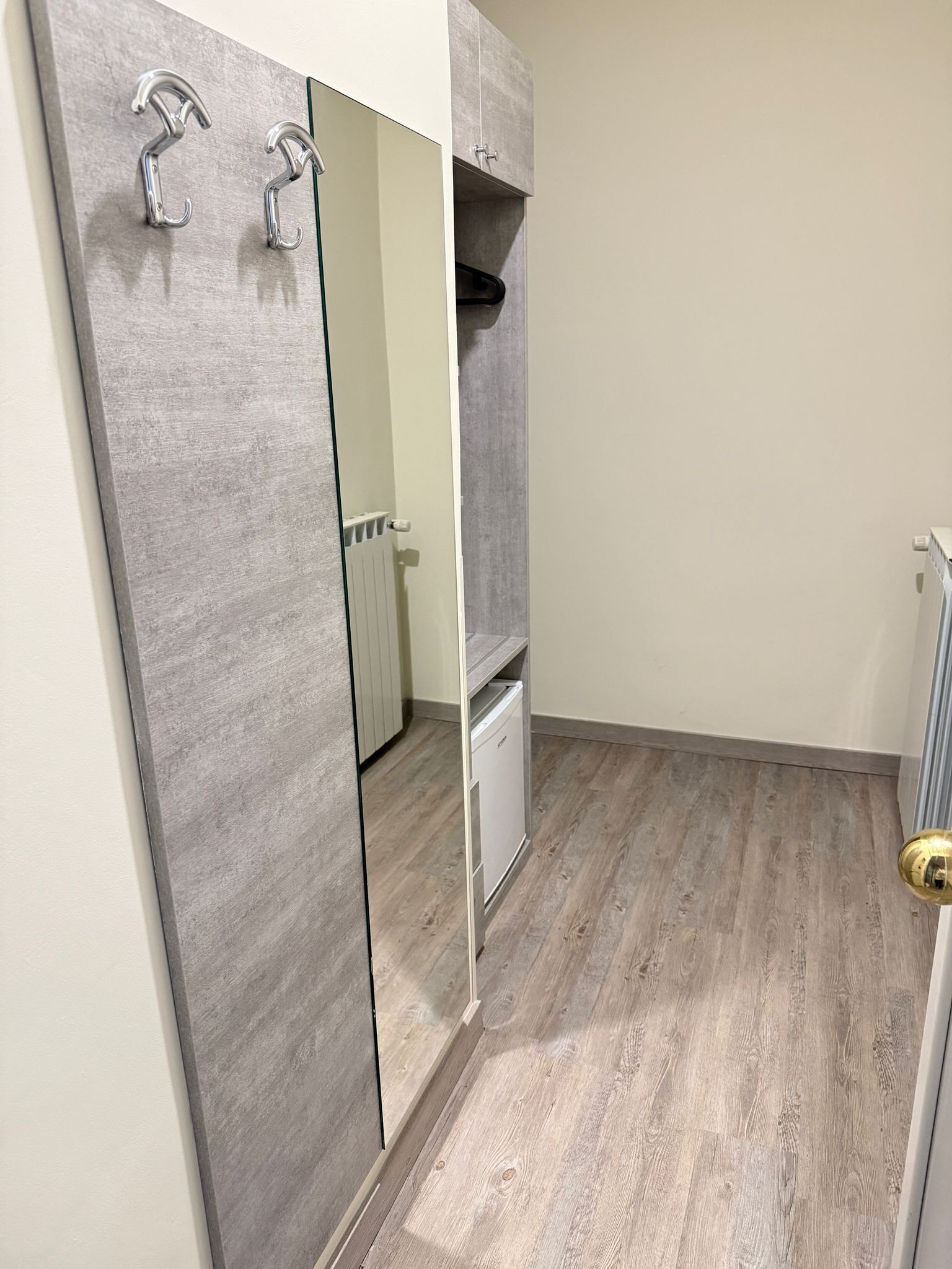 A small, modern bathroom with a grey vanity, a mirror, and a white cabinet.