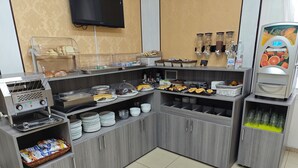 A self-service breakfast station with various food items, a coffee machine, and a beverage dispenser. - Hotel Esperia (Sanremo)