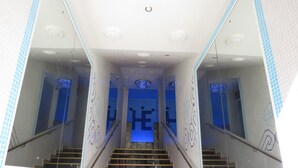 A staircase with glass railings and a mirrored wall, leading to a room with a blue-lit ceiling. - Hotel Esperia (Sanremo)