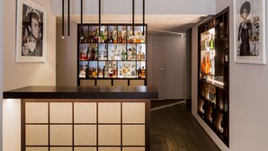 A bar area with shelves of liquor bottles, a wooden counter, and hanging light fixtures. - Palazzo Segreti (Milan)