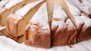 A cake with powdered sugar on a white cake stand.