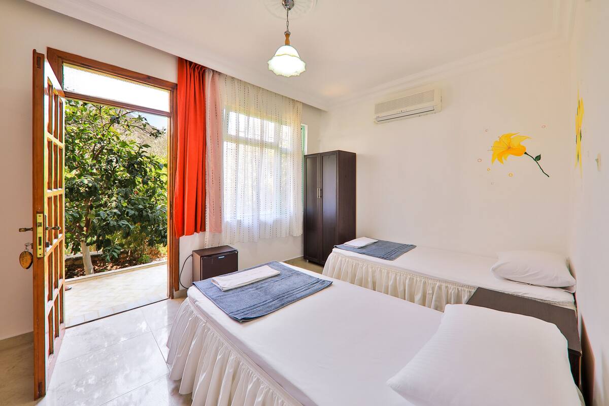 Habitación de hotel con dos camas, un armario, un escritorio y vista a zonas verdes.