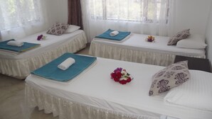 Quarto de hotel com duas camas de solteiro, cada uma com um edredom branco, uma toalha azul e uma almofada decorativa.