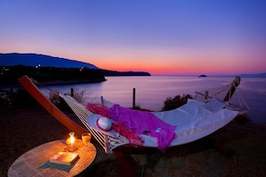 A hammock set up on a grassy area overlooking a body of water with a sunset in the background. - Monambeles Villas (Kefalonia)