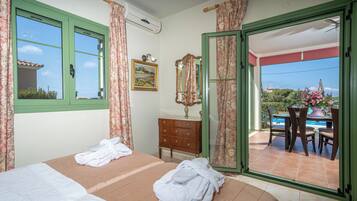 Une chambre d’hôtel avec deux lits, une commode en bois, un miroir et une vue sur l’espace extérieur de la piscine.
