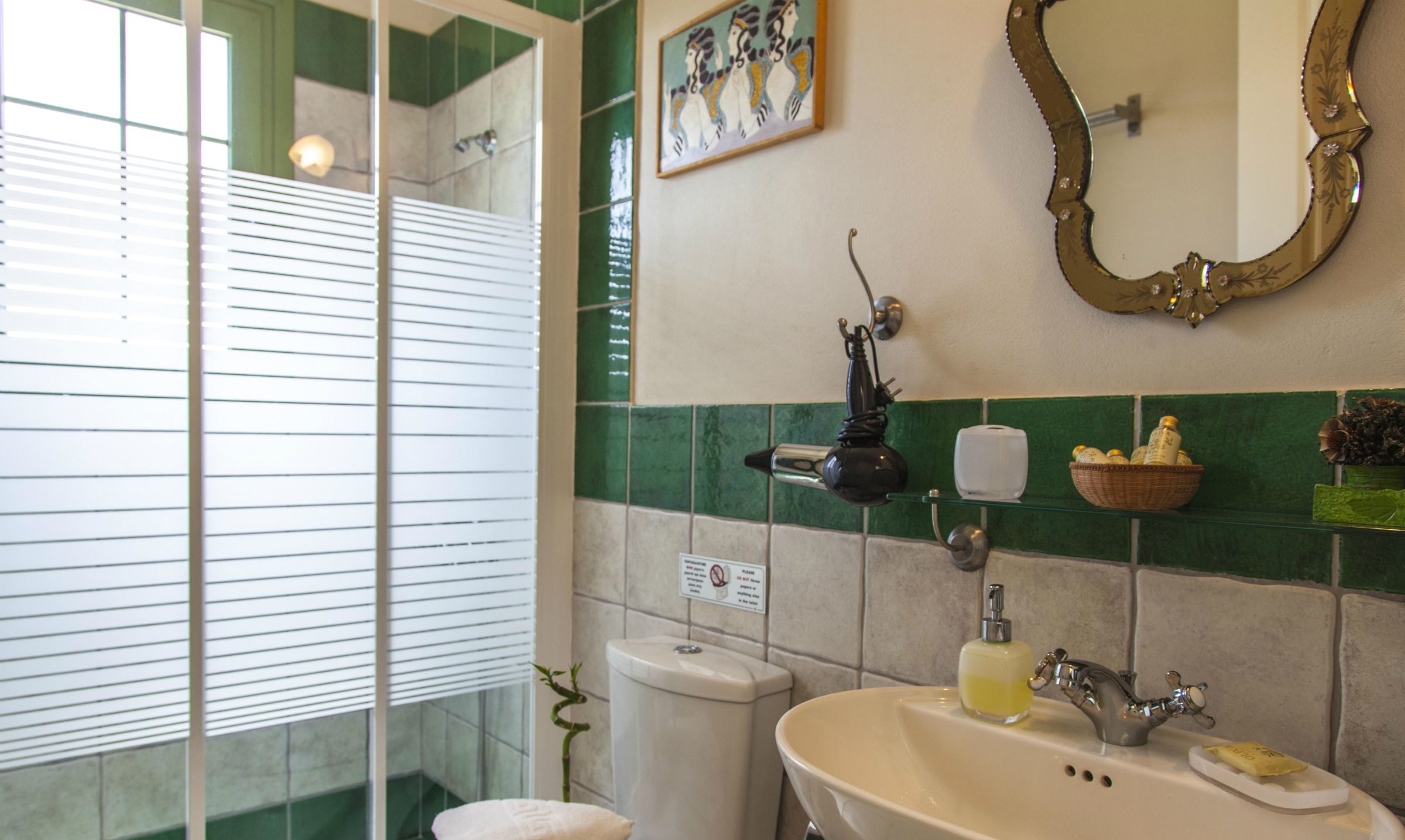 A bathroom with a sink, mirror, and a green tiled wall.