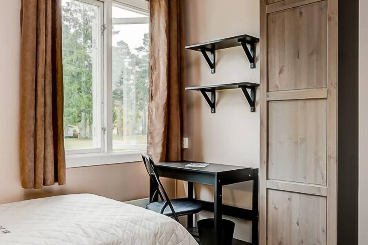 A bedroom with a bed, a desk, and a wardrobe.