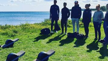 En grupp människor som står på en gräsyta vid ett vattendrag.
