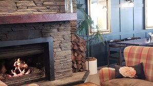 Un salón con chimenea de piedra, muebles a cuadros y una pared de acento azul.