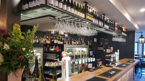 Una zona de bar con diversas botellas de licores, copas de vino y una grifo de cerveza.