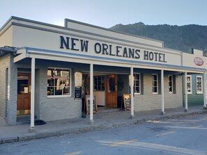 Exterior del Hotel New Orleans con un letrero, una pequeña tienda y vista de la calle.