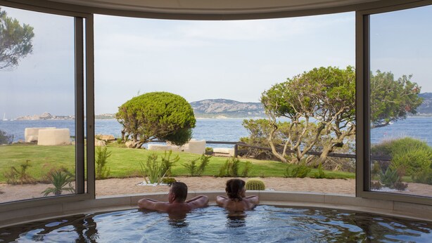 Een koppel ontspant in een jacuzzi met een prachtig uitzicht op zee en bergen.