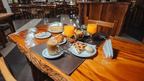 Una mesa de desayuno con cruasanes, un muffin, un vaso de jugo de naranja y una taza de café.