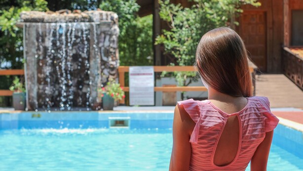 Un área de piscina con una cascada y una valla de madera.