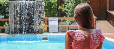 Una piscina al aire libre, sombrillas, sillones reclinables de piscina