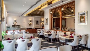 A restaurant with white chairs and tables, a counter with a display case, and decorative wall art.