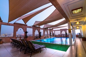 A rooftop pool area with lounge chairs and a view of the city skyline.