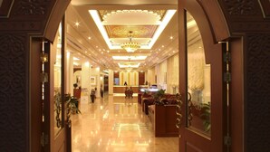 A spacious lobby with a high ceiling, ornate archway, and a reception desk.