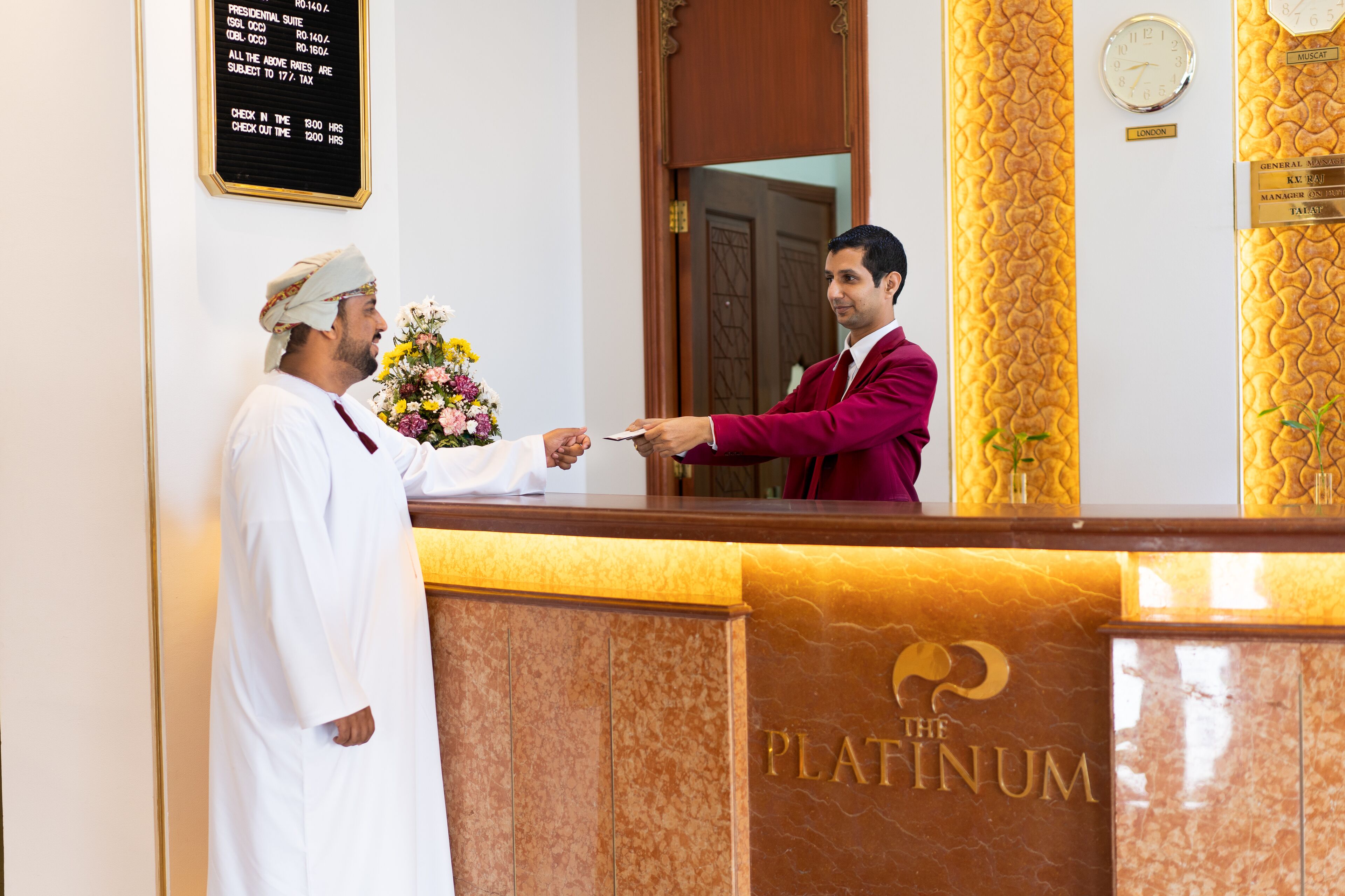 A reception desk with a plaque reading "The Platinum" and a clock on the wall.