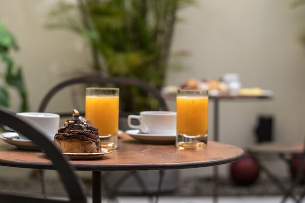 Una mesa con un muffin, dos vasos de zumo de naranja y una taza de café.