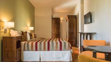 A hotel room with a bed, bedside tables, a chair, a TV, and a wooden wardrobe.