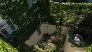 A courtyard with a checkered floor, surrounded by lush greenery and potted plants. - Magnolia Hotel Boutique (Buenos Aires)