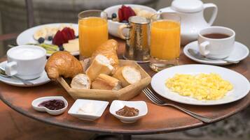Une table de petit-déjeuner avec des croissants, des œufs brouillés, des fruits et des boissons.