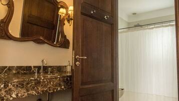 A bathroom with a wooden door, a marble sink, and a shower with a curtain.