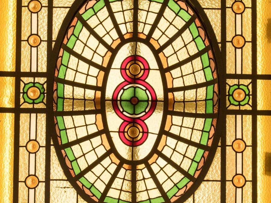 A stained glass window with a circular design and a central green and red motif.