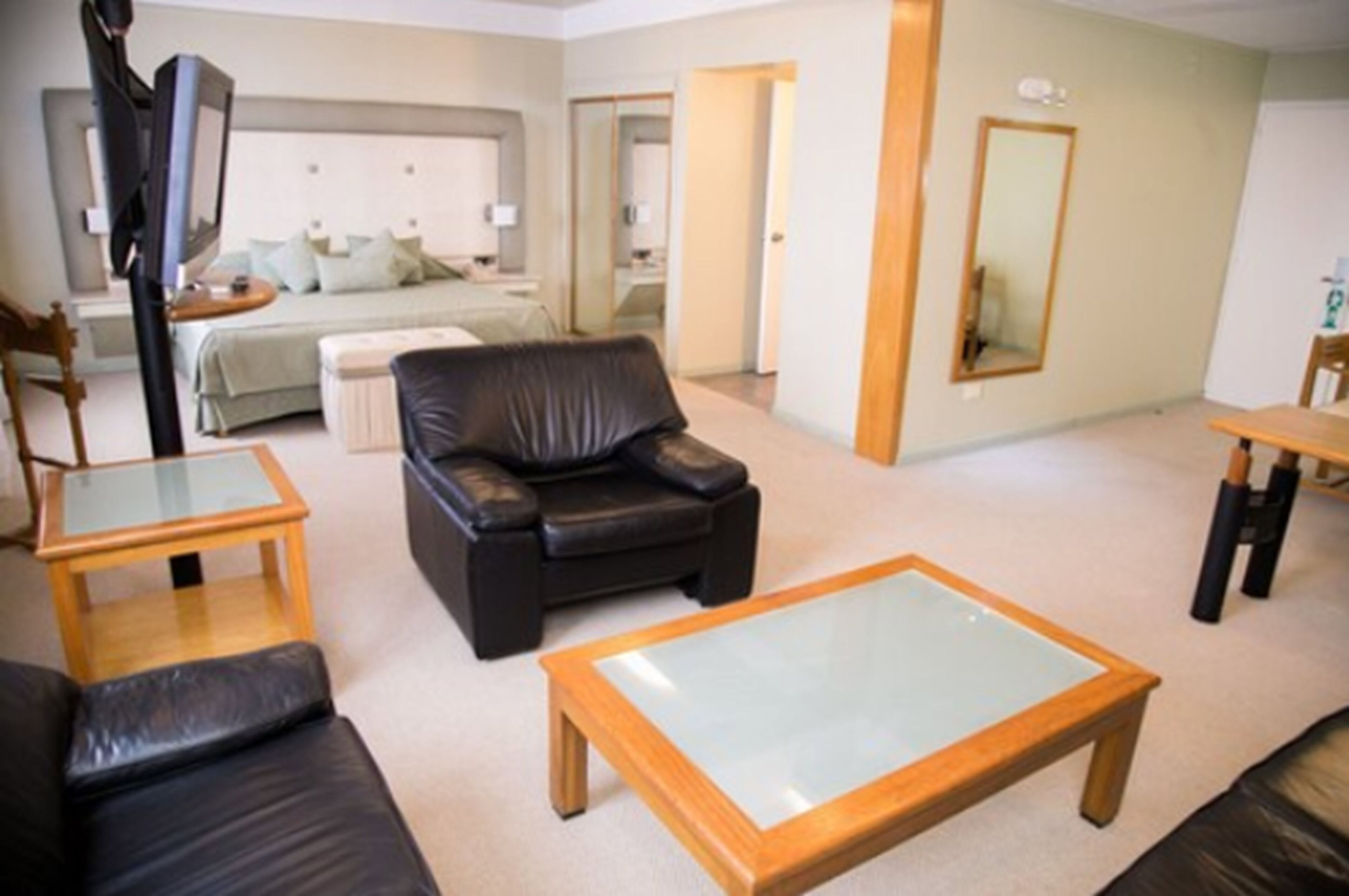 A modern living room with a leather sofa, glass coffee table, and a small wooden table.