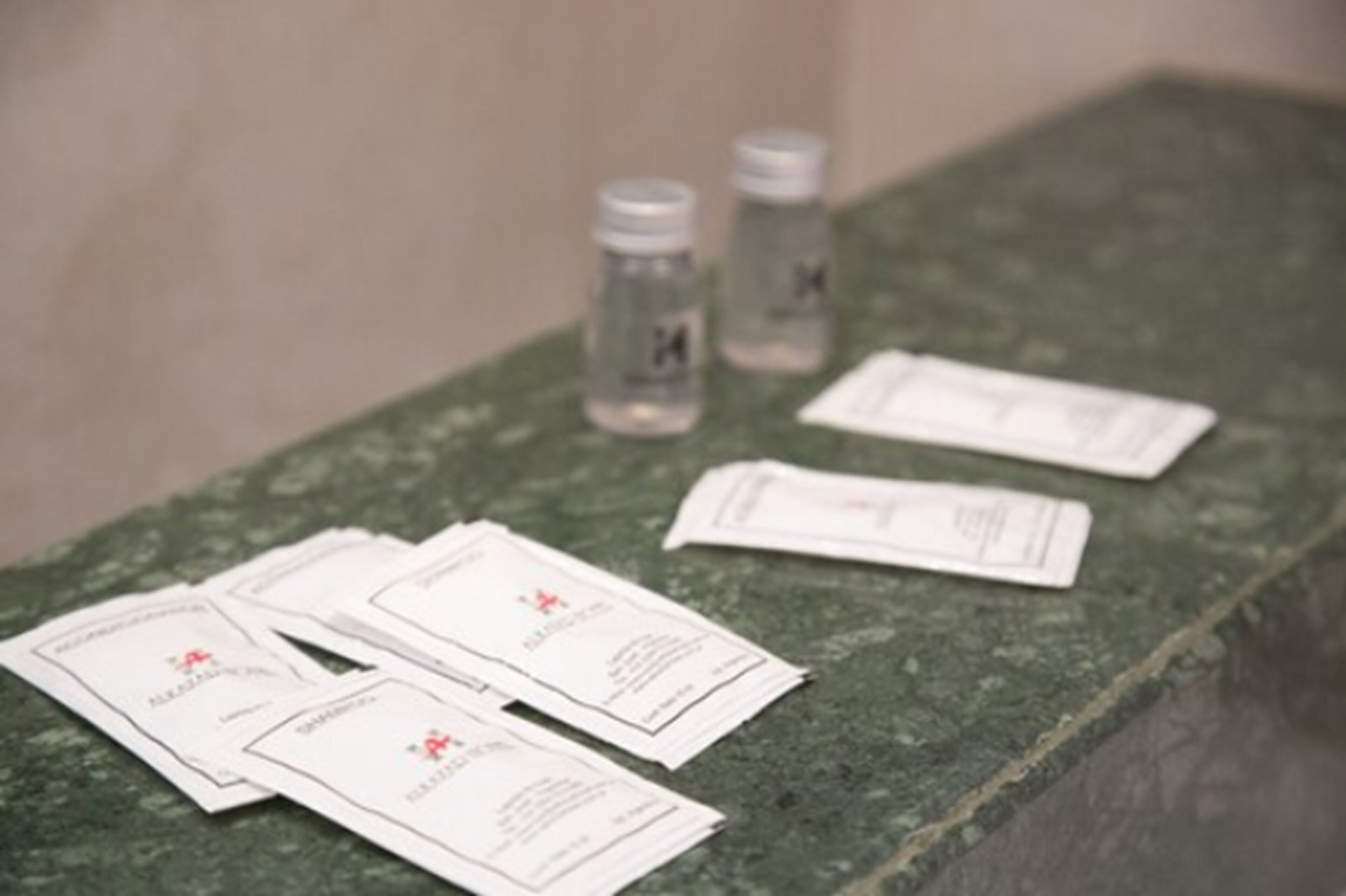 A green marble surface with several white cards and two clear bottles with labels.