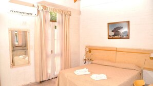 Une chambre à coucher avec un lit, une table de chevet, une lampe, un miroir et un tableau accroché au mur.