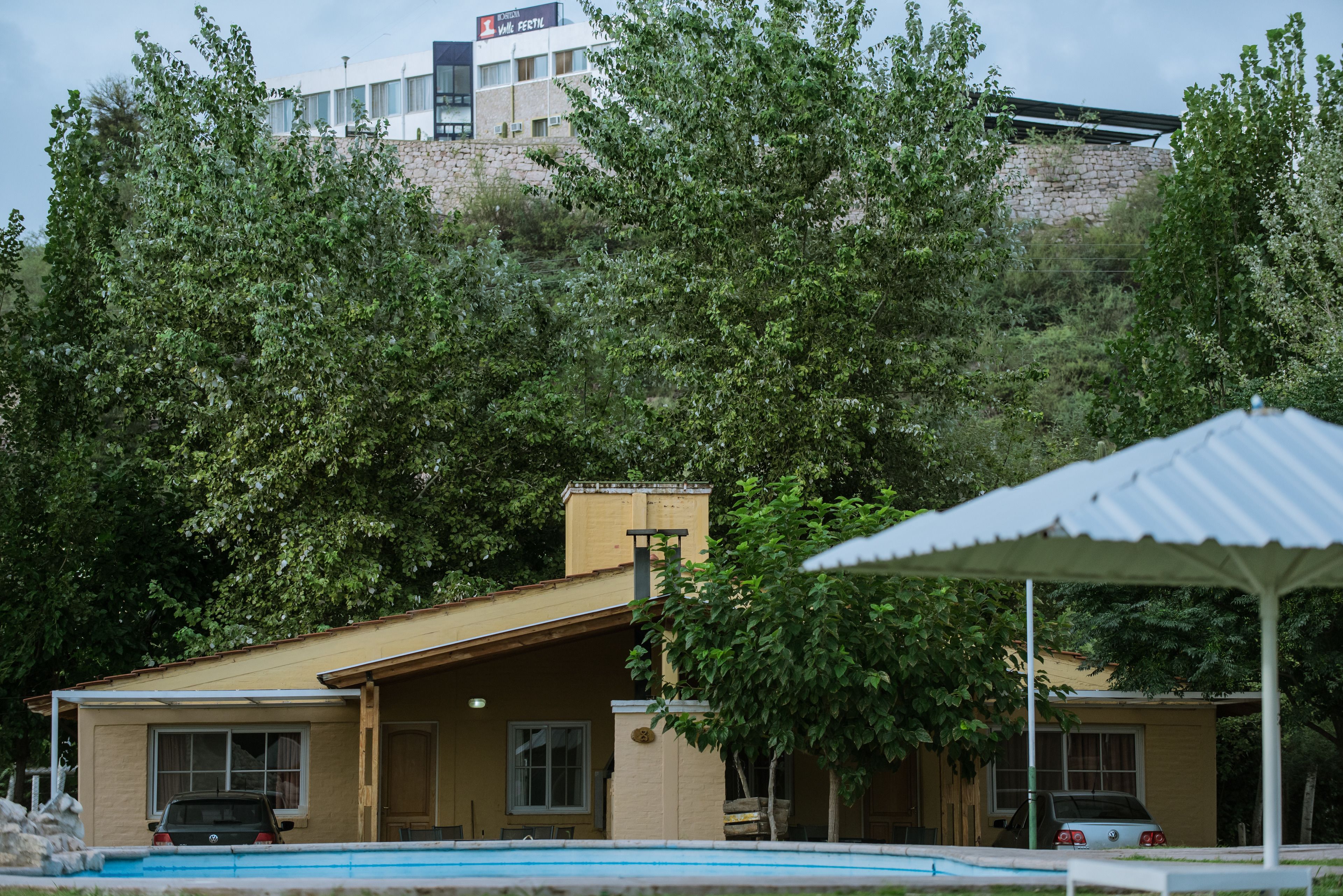 A building with a swimming pool, surrounded by trees.