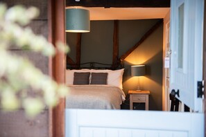 A bedroom with a bed, bedside table, lamp, and a wooden ceiling beam. - The Talkhouse (Oxford)
