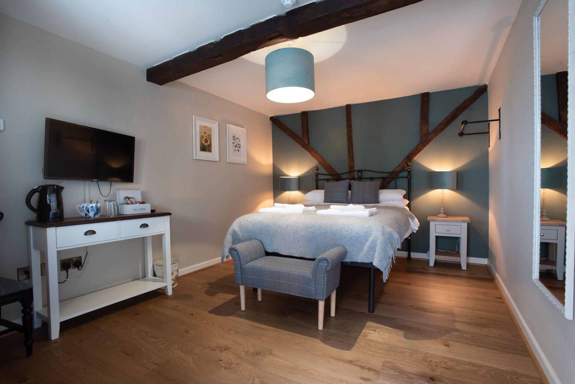 Una camera da letto con un letto, comodini, una scrivania, una sedia, una televisione e una lampada a soffitto.