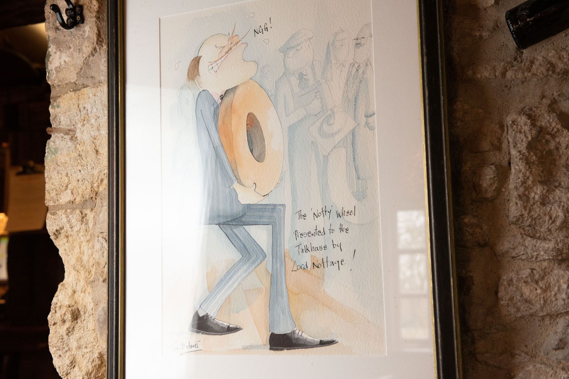 A framed watercolor painting of a man with a large orange circle on his head, signed by the artist.
