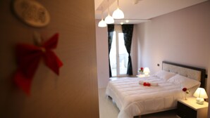 A neatly made bed with white linens and a red bow decoration on the wall. - Albion Hotel (Golem)