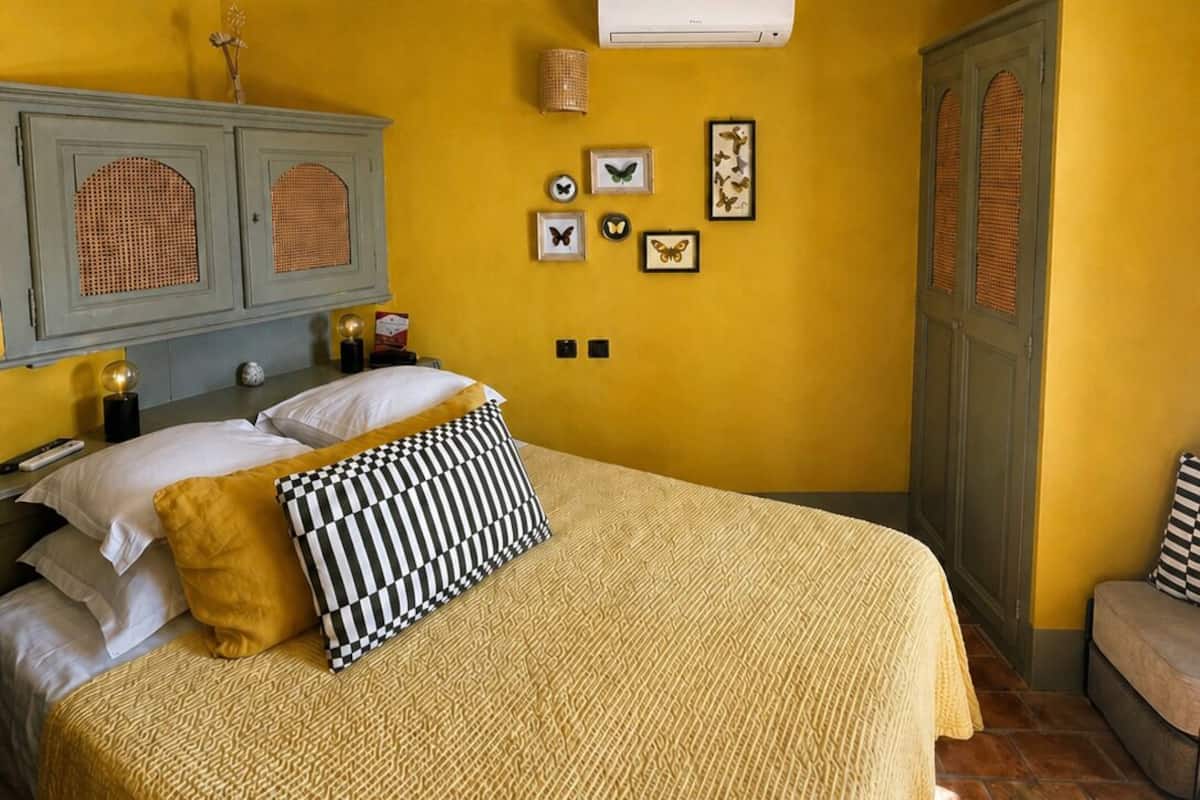 Een slaapkamer met een bed, een kledingkast, een wandairconditioner en lijstjes met vlinder afbeeldingen.