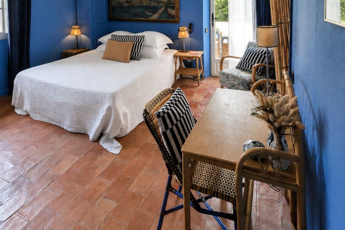 Een hotelkamer met een bed, twee nachtkastjes, een stoel, een tafel en een schilderij aan de muur.