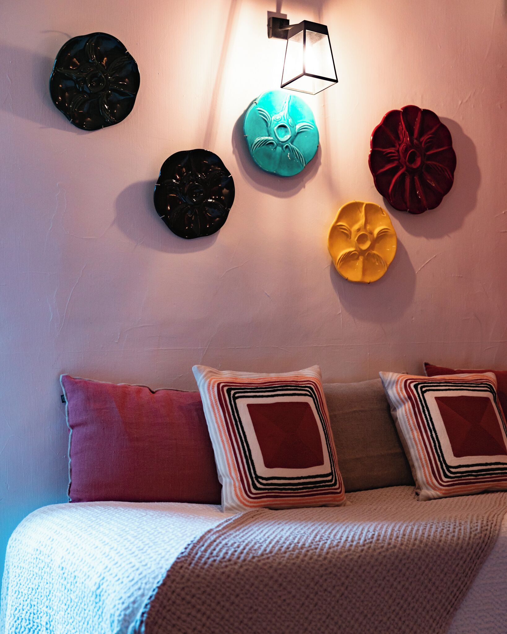A bed with multiple pillows and wall-mounted decorative plates.