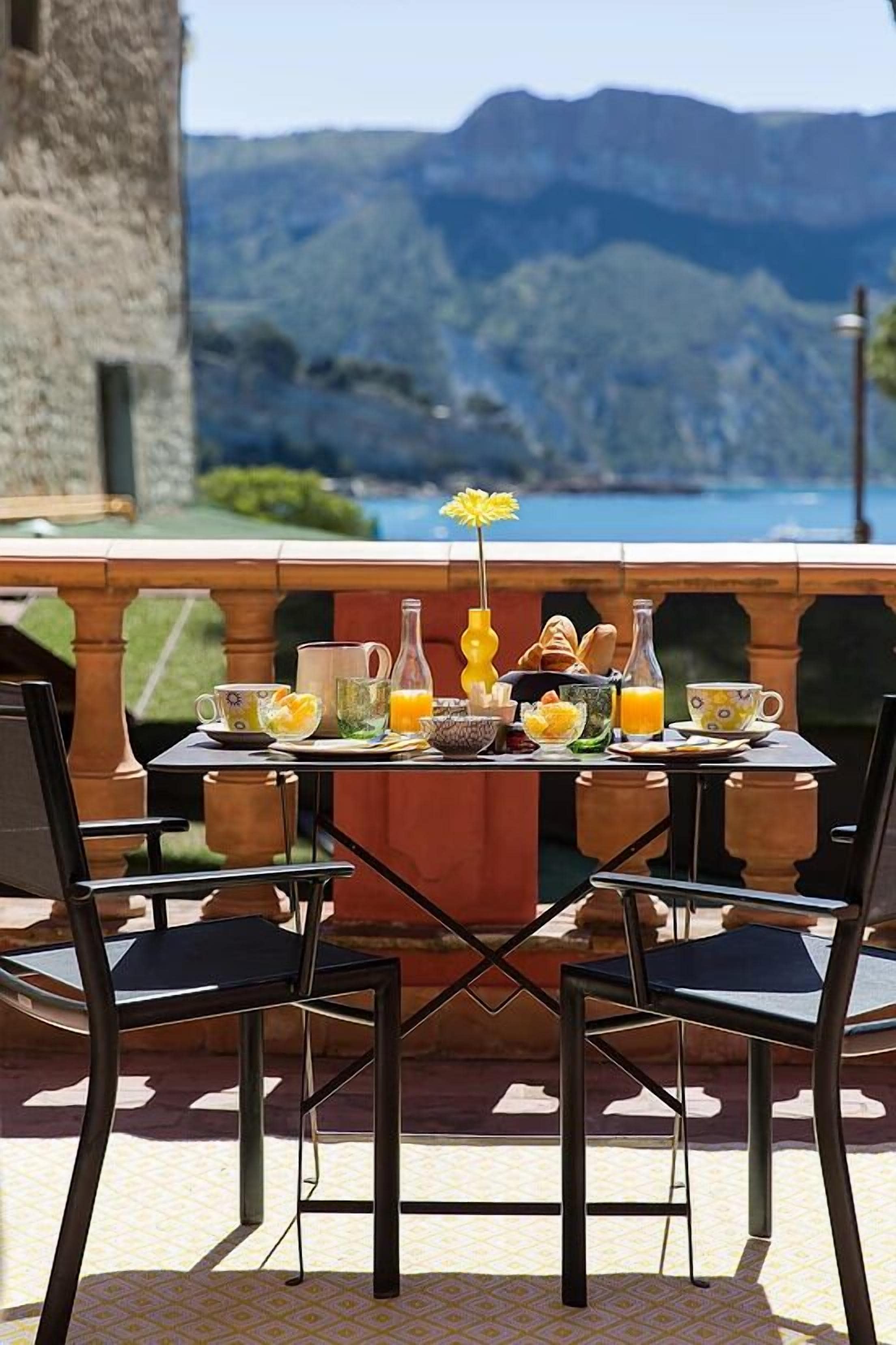 A breakfast table set on an outdoor terrace with a scenic mountain view in the background.