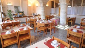 A restaurant with multiple tables and chairs, stone columns, and a counter with food and drinks. - Hotellerie Saint Yves (Chartres)